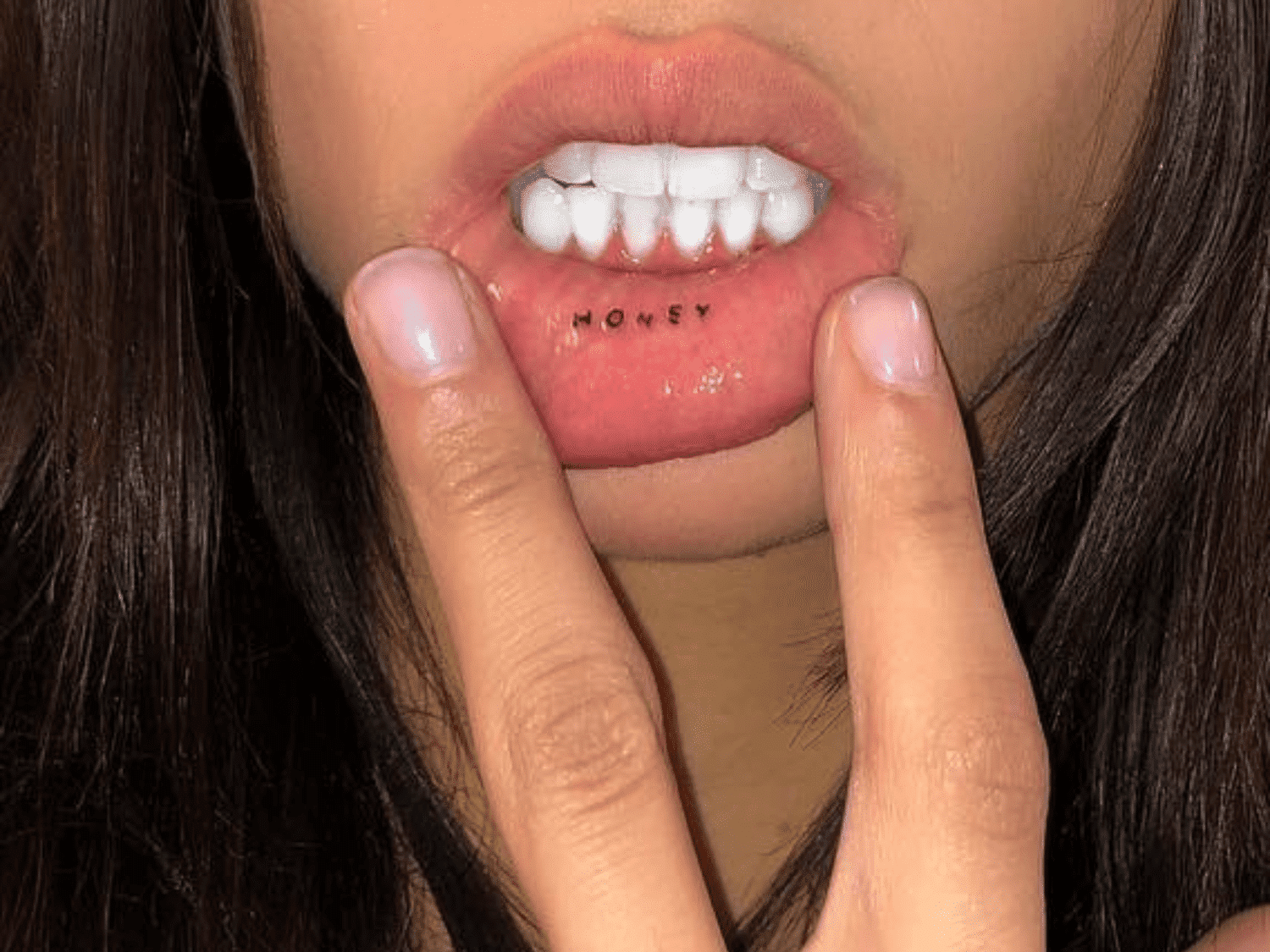 Fresh inner lip tattoo reading HONEY placed on lower lip showing typical placement scale and font